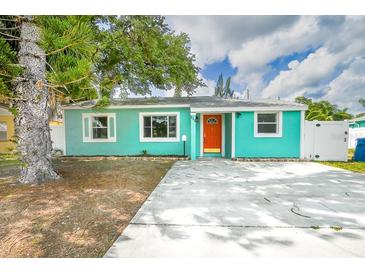 Charming single-story home with a bright teal exterior and orange door, surrounded by mature trees and a concrete driveway at 115 41St Ne Ave, St Petersburg, FL 33703