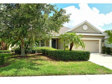 Charming single-story home featuring a manicured lawn, lush landscaping, and an attached two-car garage at 12331 Halfmoon Lake Ter, Bradenton, FL 34211