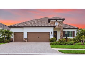Beautiful single-story home featuring a brick driveway, three-car garage, and stone facade accent at 13606 Deep Blue Pl, Bradenton, FL 34211