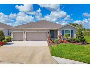 Charming home featuring a three-car garage and a well-maintained lawn with colorful landscaping at 16606 Barnwood Pl, Lakewood Ranch, FL 34211