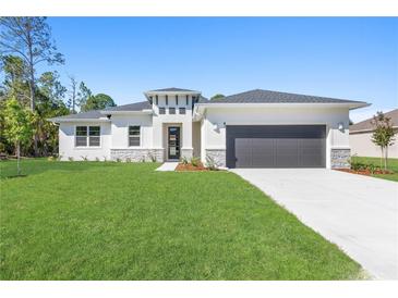 Charming single-story home featuring a well-manicured lawn and a neutral color palette with decorative stone accents at 18100 Poston Ave, Port Charlotte, FL 33948