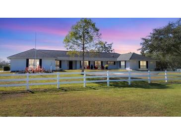 Home with a circular driveway, white fence, and green grass with the sky turning from dusk to night at 2005 21St W St, Palmetto, FL 34221