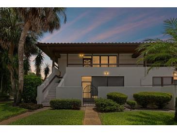 Inviting condo exterior showcases a private courtyard entrance, lush tropical landscaping, and a charming second-story balcony at 3500 El Conquistador Pkwy # 132, Bradenton, FL 34210