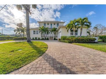Charming two-story home boasts a brick driveway and lush tropical landscaping, creating a welcoming curb appeal at 634 Key Royale Dr, Holmes Beach, FL 34217
