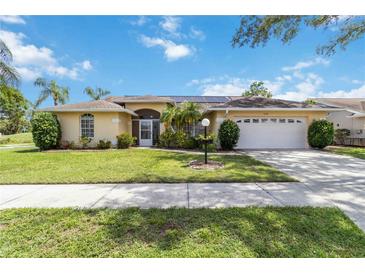 Charming single-story home with a well-manicured lawn, palm trees, and attached two car garage at 6405 Alesheba Ln, Sarasota, FL 34240