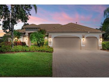 Charming single-story home with a well-maintained lawn, beautiful landscaping, and a beige tile roof at 6528 Coopers Hawk Ct, Lakewood Ranch, FL 34202