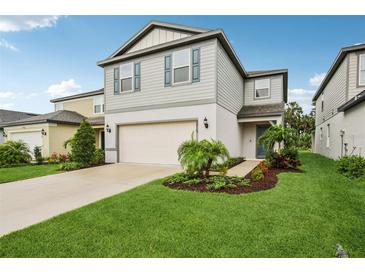 Charming two-story home featuring a manicured lawn, attached garage, and attractive landscaping at 8815 Windlass Cv, Parrish, FL 34219