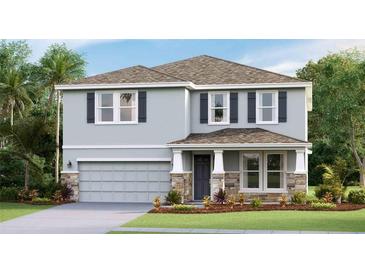 Charming two-story home featuring a stone facade, light gray siding and a well-manicured lawn at 12047 Kingsley Trl, Parrish, FL 34219