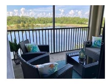 A screened balcony featuring wicker furniture offers serene lake views at 16804 Vardon Ter # 307, Bradenton, FL 34211