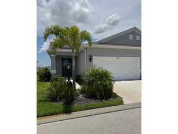 Charming single-story home with a well-maintained lawn, palm trees, and a two-car garage at 24827 Buckingham Way, Port Charlotte, FL 33980