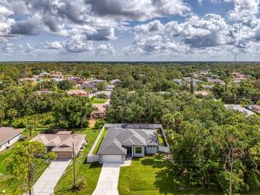 Beautiful aerial view of a charming home with a screened-in pool nestled among lush trees and landscaping at 2546 Malibu Ln, North Port, FL 34286