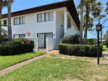 Inviting two-story condo with white exterior, brown trim, lush landscaping, and an iron gate entry at 3500 El Conquistador Pkwy # 347, Bradenton, FL 34210