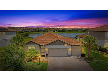 Stunning sunset view of single-Gathering home with lake view and lush landscaping with a three-car garage at 3504 Big Sky Way, Bradenton, FL 34211