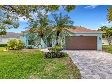 Charming single-story home features a well-manicured lawn, brick driveway, and lush tropical landscaping at 4120 51St W Dr, Bradenton, FL 34210