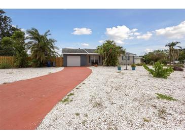 Charming single-story home with a red driveway, white rock landscaping, and vibrant tropical foliage at 4303 83Rd W St, Bradenton, FL 34209