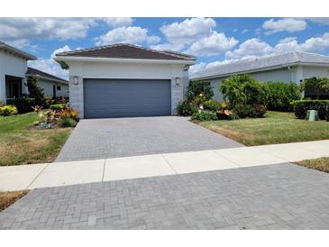 Charming home featuring a paved driveway leading up to a garage with gray door, surrounded by lush landscaping at 5219 Barnett Cir, Bradenton, FL 34211