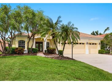 Inviting home featuring a tile roof, a well-manicured lawn, palm trees, and a three-car garage at 6811 Honeysuckle Trl, Lakewood Ranch, FL 34202