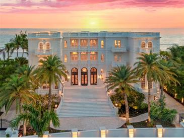 Stunning beachfront estate with multi-level balconies, lush palms, grand entrance, and breathtaking sunset views at 845 Longboat Club Rd, Longboat Key, FL 34228