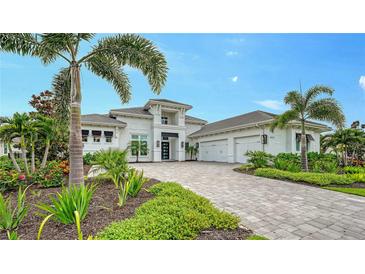 Stunning white home with a paver driveway, lush landscaping, and palm trees at 8537 Pavia Way, Bradenton, FL 34202