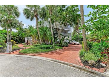 Stately three-story home featuring lush tropical landscaping and a red brick circular driveway at 8963 Fishermens Bay Dr, Sarasota, FL 34231