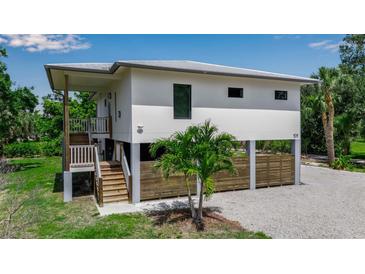 Stunning elevated home featuring a modern design, a wooden fence and staircase and a well-manicured lawn at 105 Shore Rd, Nokomis, FL 34275