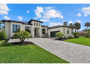 Contemporary home showcasing a paved driveway, lush lawn, and modern architectural details at 1605 Landfall Dr, Nokomis, FL 34275