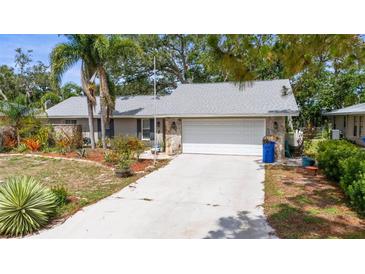 Charming single-story home featuring a stone facade and attached two car garage, enhanced by lush landscaping and mature trees at 2204 67Th W St, Bradenton, FL 34209