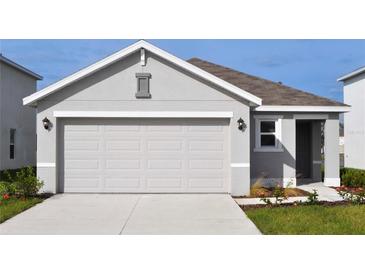Two car garage door and driveway to a one-story home with gray stucco exterior under a bright blue sky at 3278 Rock Sound St, Bradenton, FL 34208