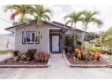Charming home with lush landscaping, a brick walkway, and tropical palm trees at 4945 Camphor Ave, Sarasota, FL 34231