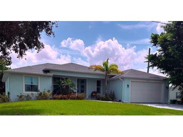 Charming single story home featuring a lush lawn, lovely landscaping, and a light blue exterior at 831 Palmetto Ne Dr, Port Charlotte, FL 33952