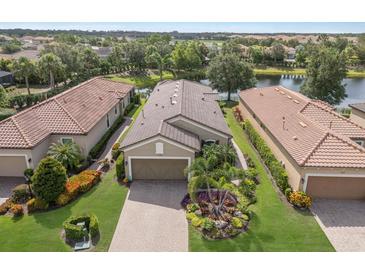 Stunning aerial view of the home with tile roof, brick driveway, and lush landscaping by the pond at 13338 Torresina Ter, Lakewood Ranch, FL 34211
