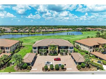 Exterior view of a multi-Gathering home overlooking a lake and golf course, with lush landscaping and ample parking at 13609 Messina Loop # 104, Bradenton, FL 34211
