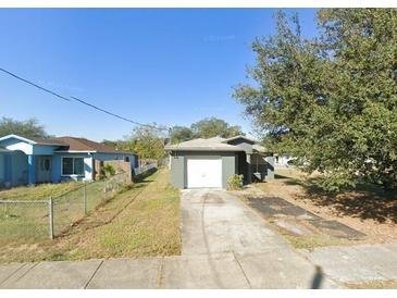 View of the home's exterior and front yard featuring a driveway leading up to a one-car garage and landscaping at 3622 N 51St St, Tampa, FL 33619