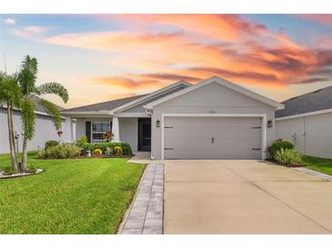 Charming single-story home featuring a well-manicured lawn and two-car garage, bathed in the warm hues of a vibrant sunset at 5958 164Th E Ave, Parrish, FL 34219