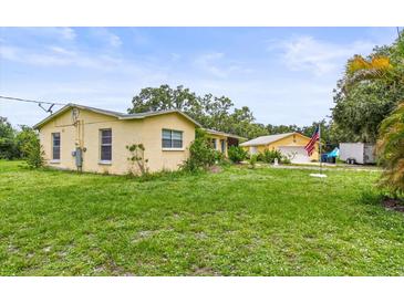 Charming yellow home with a well-maintained lawn and separate garage, creating a welcoming curb appeal at 5981 Jim Davis Rd, Parrish, FL 34219