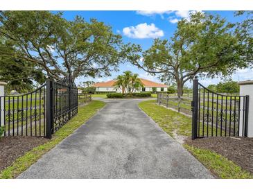 A gated entry leads to a large home with mature trees and manicured landscaping at 7025 Saddle Creek Cir, Sarasota, FL 34241