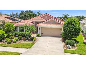 Charming single-story home featuring a red tile roof, a two-car garage, and lush landscaping in a well-maintained yard at 8906 Stone Harbour Loop, Bradenton, FL 34212