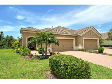 Charming home featuring a three-car garage, well-manicured lawn, and lush tropical landscaping at 1301 Backspin Dr, Englewood, FL 34223