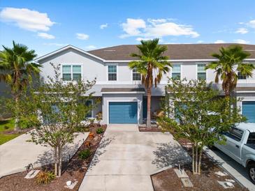 Charming townhouse with well-maintained landscaping, blue garage door, and palm trees in a sunny neighborhood at 4644 Vignette Way, Sarasota, FL 34240