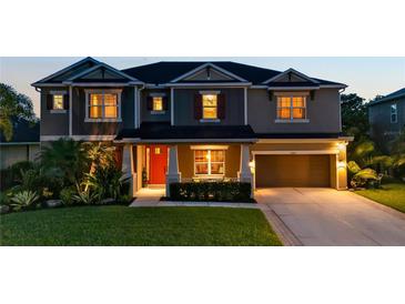 Inviting two-story home featuring a well-maintained lawn and a two-car garage, illuminated by warm exterior lighting at 6302 Anise Dr, Sarasota, FL 34238