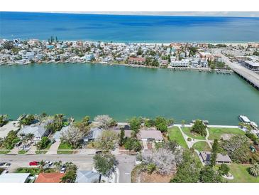 Aerial view of waterfront homes and a glimpse of the beach, offering serene coastal living at 9300 Gulf Blvd, St Pete Beach, FL 33706