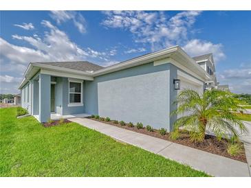 Beautiful single-story home with light-blue siding, a well-manicured lawn, and a palm tree in the front yard at 13136 Bayberry Way, Parrish, FL 34219