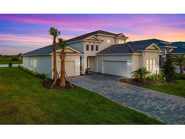 Beautiful home featuring a manicured lawn, brick driveway, and well-kept landscaping against a colorful sunset sky at 17128 Ranchside Pl, Lakewood Ranch, FL 34211
