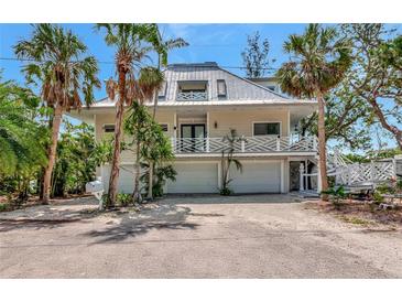 Beautiful two-story home featuring a metal roof, white accents, and tropical landscaping at 3737 Bayou Louise Ln, Sarasota, FL 34242