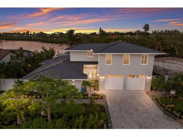 Stunning two-story home with a three-car garage, lush landscaping, and a beautiful sunset backdrop near the waterfront at 4 Winslow Pl, Longboat Key, FL 34228