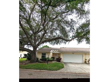 Charming single story home with an attached garage, walkway, and a shade tree in a well-maintained front yard at 4131 Oakhurst W Cir # 3133, Sarasota, FL 34233