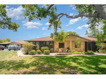 Charming single-story home featuring a screened patio with lush landscaping and mature trees on a sunny day at 4165 66Th Street W Cir # H, Bradenton, FL 34209