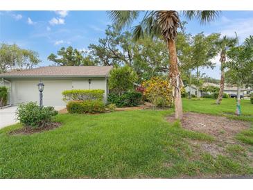 Well-maintained home exterior with lush lawn and tropical landscaping with palm trees at 4637 Willow Wood Cir # 44, Sarasota, FL 34241