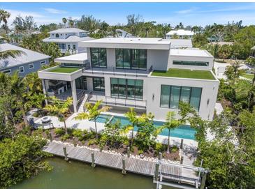 Modern home with a pool, dock, and lush landscaping, perfect for waterfront living at 590 De Narvaez Dr, Longboat Key, FL 34228