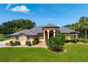 Stunning single story home with well manicured lawn, lush landscaping, and charming covered front porch at 8312 Misty Lake Cir, Sarasota, FL 34241